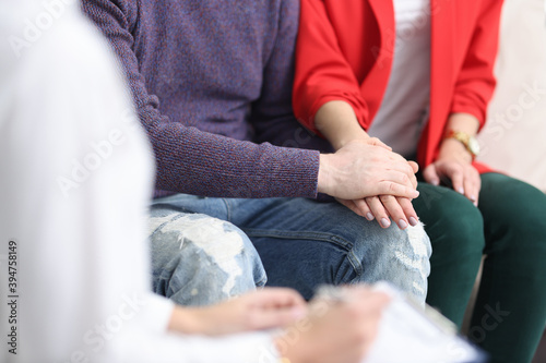 Man holding a womans hand and calming down at psychologists appointment closeup. Psychological assistance to families concept