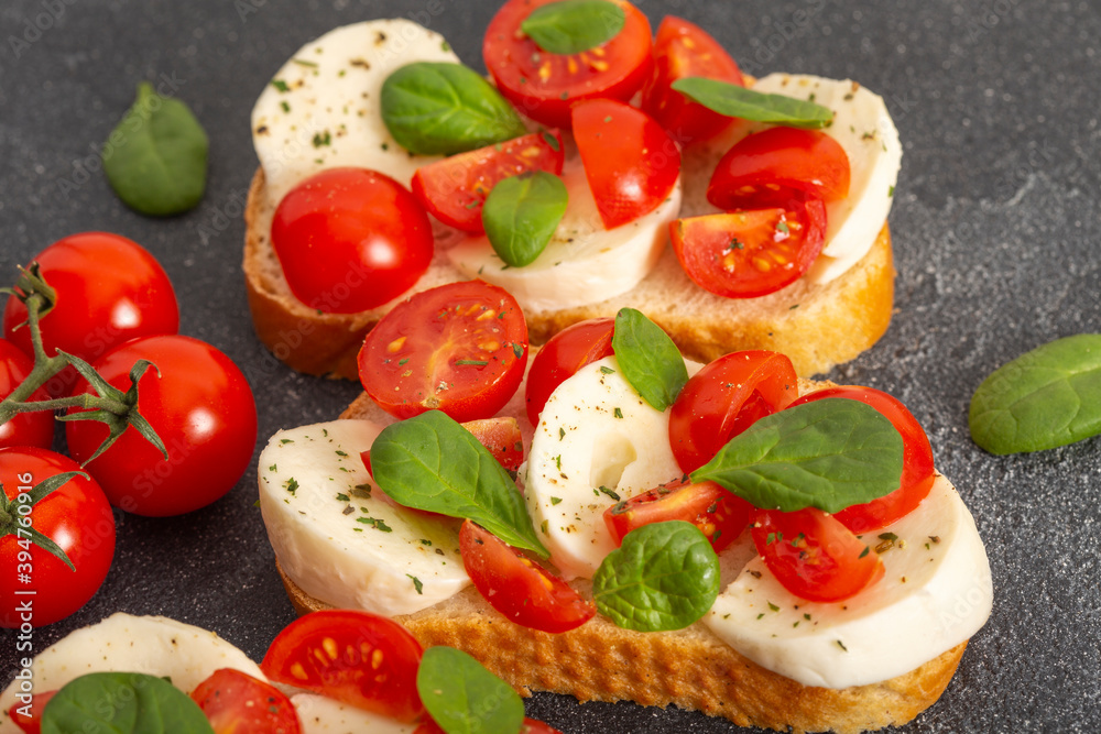 Caprese bruschetta toasts with mozzarella, cherry tomatoes and fresh garden basil.Traditional italian appetizer or snack, antipasto. Top view with copy space. Flat lay. Caprese bruschetta toasts with mozzarella, cherry tomatoes and fresh garden basil.Traditional italian appetizer or snack, antipasto. Top view with copy space. Flat lay.
