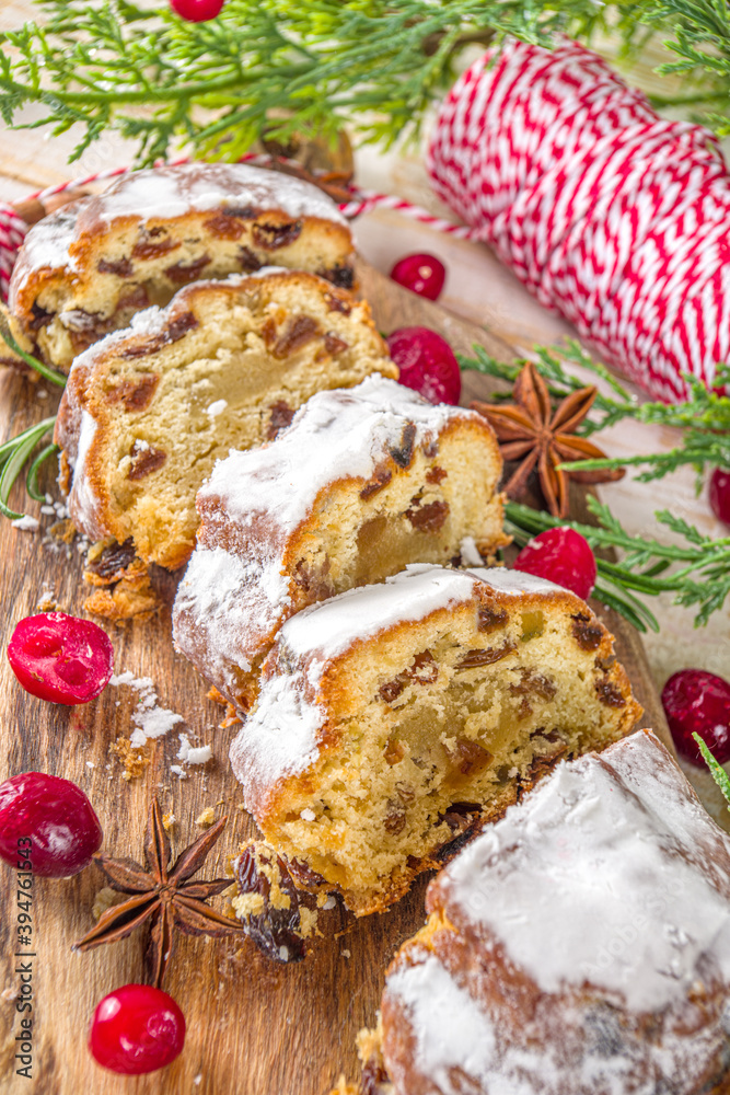 Christmas stollen with icing sugar, marzipan and raisins. Traditional Dresden christ pastry. On table background with fir tree branches and Christmas decoratioon top view copy space Christmas stollen with icing sugar, marzipan and raisins. Traditional Dresden christ pastry. On table background with fir tree branches and Christmas decoratioon top view copy space