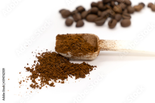 Ground coffee with plastic white spoon and coffee beans isolated on white background.