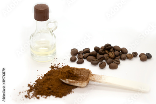 Ground coffee with plastic white spoon, coffee beans and a bottle of vanilla isolated on white background.
