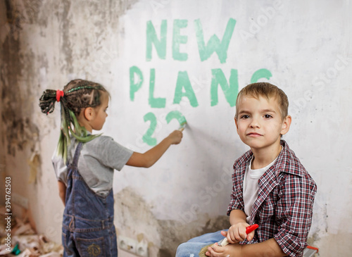 Father with kids repairing room together, unhanging wallpaper and planning new year on wall photo