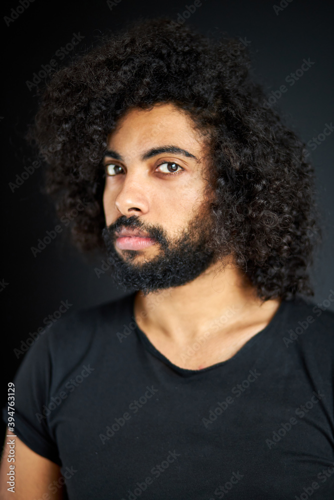 portrait of pleased arab man isolated in studio, handsome guy in casual wear posing at camera, has black long curly hair, calm male of indian or arabian appearance portrait of pleased arab man isolated in studio, handsome guy in casual wear posing at camera, has black long curly hair, calm male of indian or arabian appearance