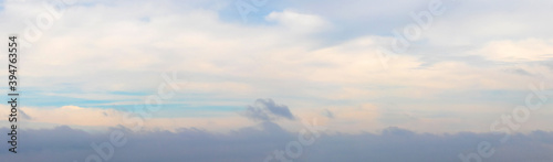 Panorama of the sky with a dark cloud below at sunset in soft pastel colors
