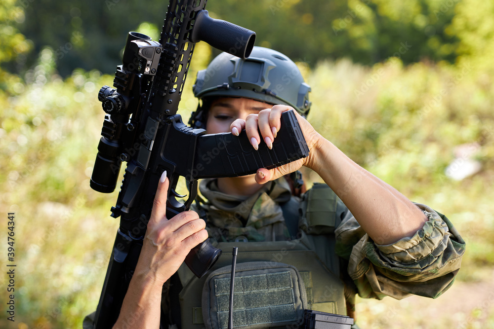 military woman is checking details of weapon before military training loading gun outdoors, sport shooting