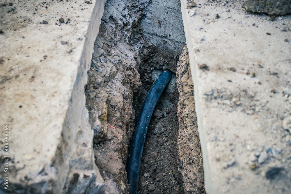 Optical cable in a excavated trench deep in the ground. Excavation and installation of underground telephone, electric or fast internet fiber optic cables. Optical cable in a excavated trench deep in the ground. Excavation and installation of underground telephone, electric or fast internet fiber optic cables.