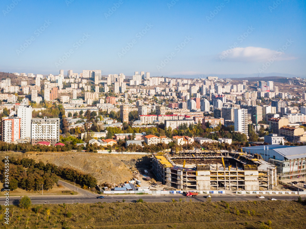 Olympc palace building with stadium construction site and Saburtalo district area real estate buildings in the background
