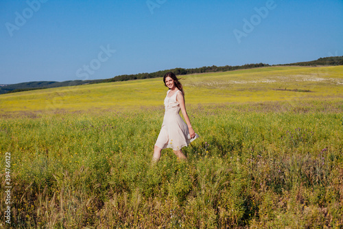 Beautiful woman in dress walks on the field happily one