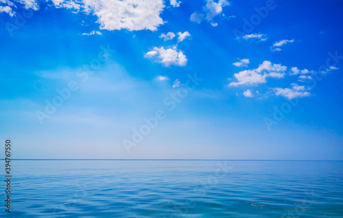 Calm sea and crystal clear sky and straight horizon with some clouds