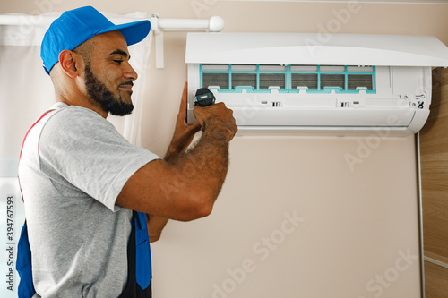 Professional repairman installing air conditioner in a room
