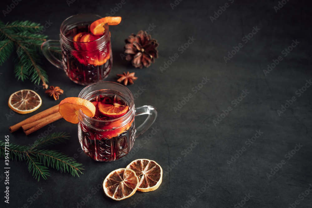 Traditional Christmas hot mulled wine. Hot drink with spices in glass cup on dark background.