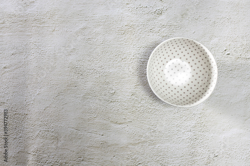 Ceramic bowl and spoon is on a cement table top. Place for text