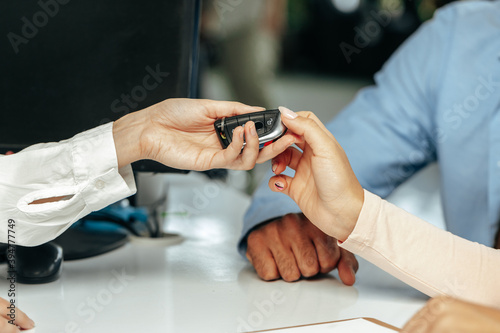 Car salesperson giving keys to a client close up