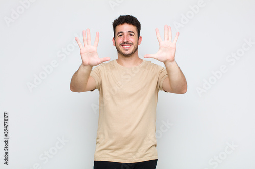 young man smiling and looking friendly, showing number ten or tenth with hand forward, counting down photo