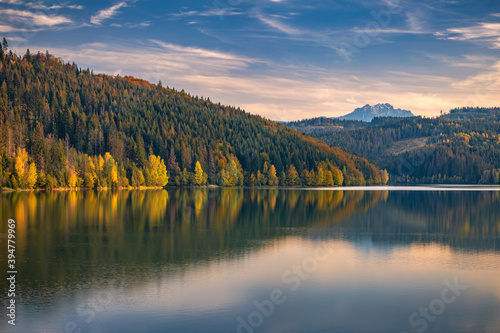 Autumn landscape with mountains on background..Mirroring of colorful forests on the water surface of the lake.