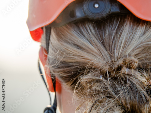 Blonde girl with climbing equipment, harnesses, carabiners, helmet and gloves at sunset. Is in a via ferrata