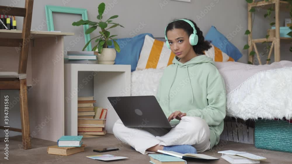 African american teen school girl distant school or college student virtual remote e learning using laptop in bedroom looking at camera. Distance education classes, studying online at home concept.