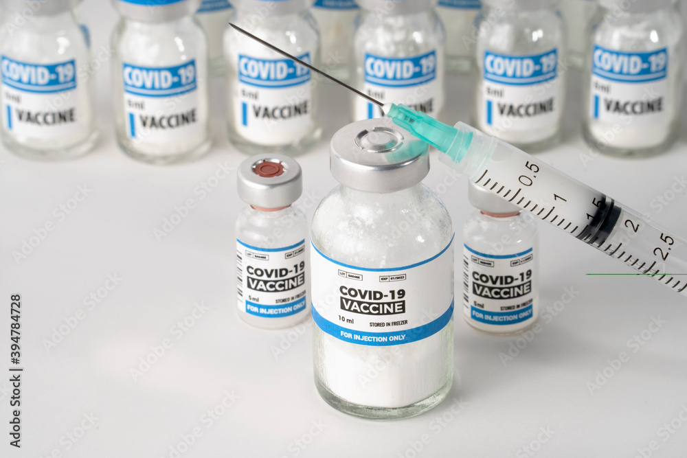 Covid-19 coronavirus vaccine injection in sealed bottles and medical disposable plastic syringe against a white background. Covid-19 coronavirus vaccine injection in sealed bottles and medical disposable plastic syringe against a white background.