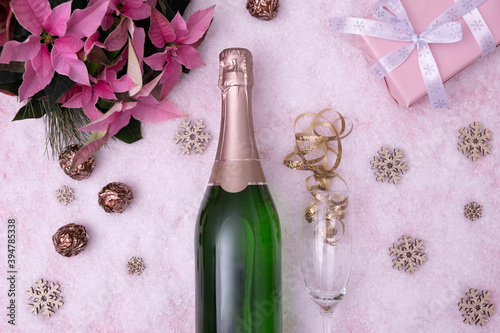 red flowers, a bottle of champagne and a gift lie on a snow-covered table