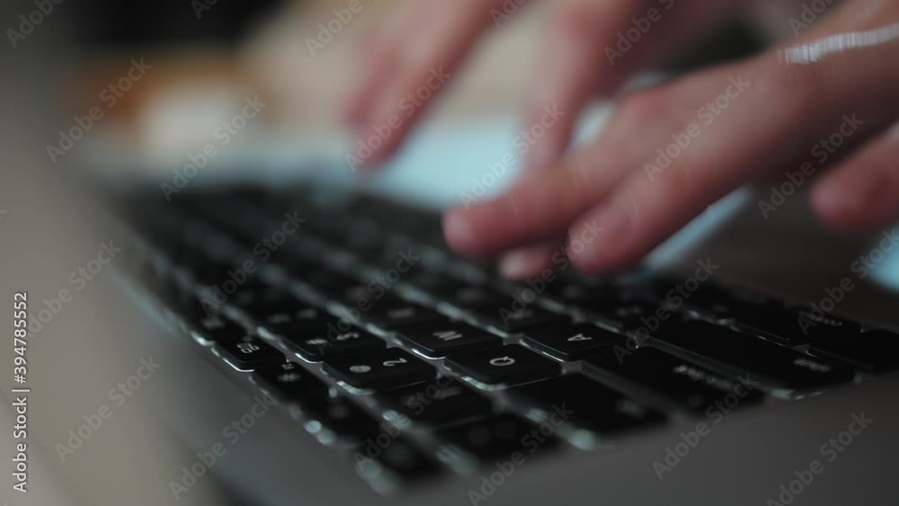 Close up macro shot of female fingers typing text on a laptop keyboard, writing emails, using the internet.