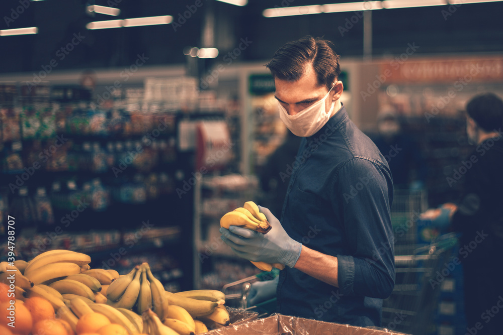 customer in protective gloves choosing bananas in a supermarket