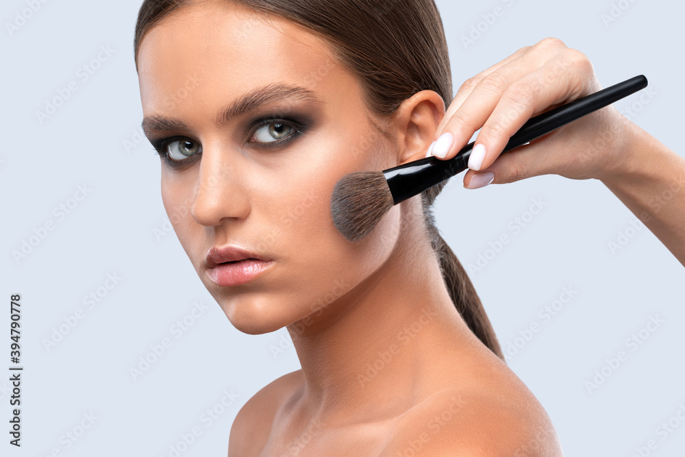 Portrait of a beautiful charming brunette teenage girl with beautiful fresh makeup and healthy clean skin.Makeup artist holds a powder brush in her hands. Professional makeup concept Portrait of a beautiful charming brunette teenage girl with beautiful fresh makeup and healthy clean skin.Makeup artist holds a powder brush in her hands. Professional makeup concept