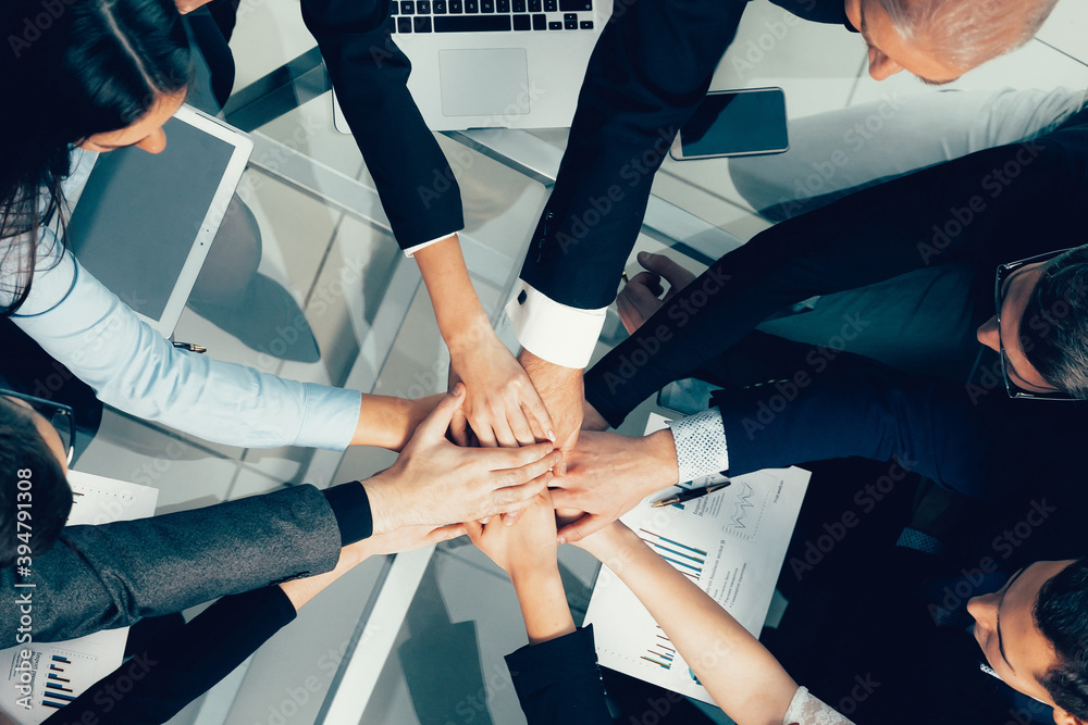 top view. happy employees joining their hands over the desktop.
