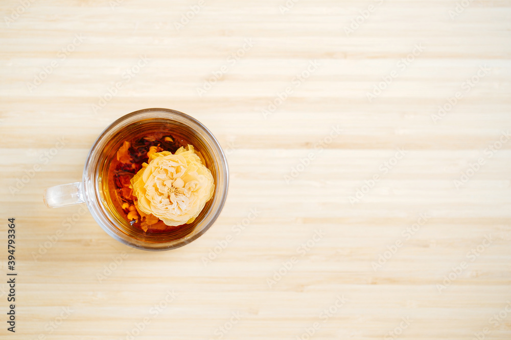 Black Chinese herbal tea with a flower inside the glass cup on the wooden background Black Chinese herbal tea with a flower inside the glass cup on the wooden background