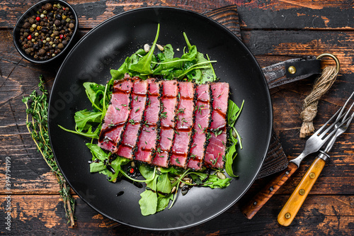 Grilled teriyaki Tuna steak salad with arugula and spinach. Dark wooden background. Top view