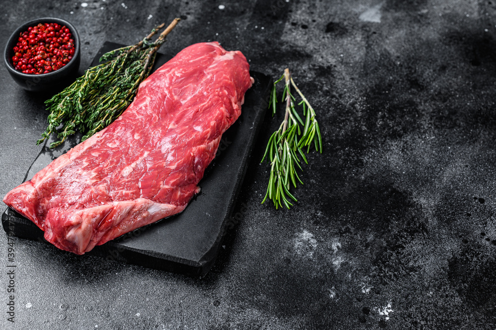 Raw flank beef meat steak. Black background. Top view. Copy space