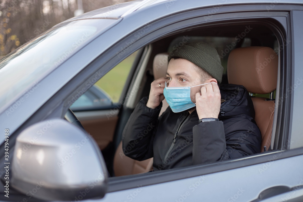 Male driver wearing mask in car during coronavirus outbreak.White