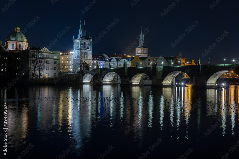 
illuminated Charles Bridge from 14 centuries and light from street lighting and stone sculptures on the bridge and light reflections on the surface of the Vltava river at night in Prague