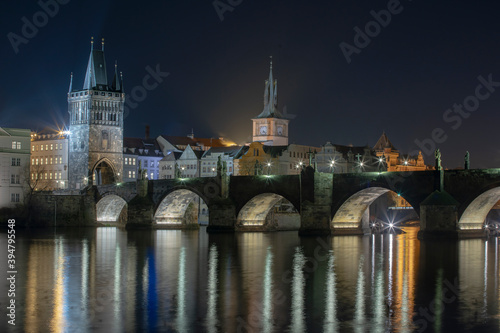  illuminated Charles Bridge from 14 centuries and light from street lighting and stone sculptures on the bridge and light reflections on the surface of the Vltava river at night in Prague © svetjekolem