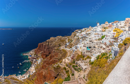 A view of the northern edge of the village of Oia, Santorini with Amoudi Bay at the base of the cliffs in summertime