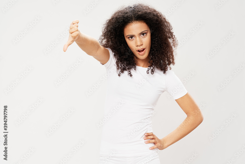 Woman with curly black hair showing thumb down white t-shirt studio Woman with curly black hair showing thumb down white t-shirt studio