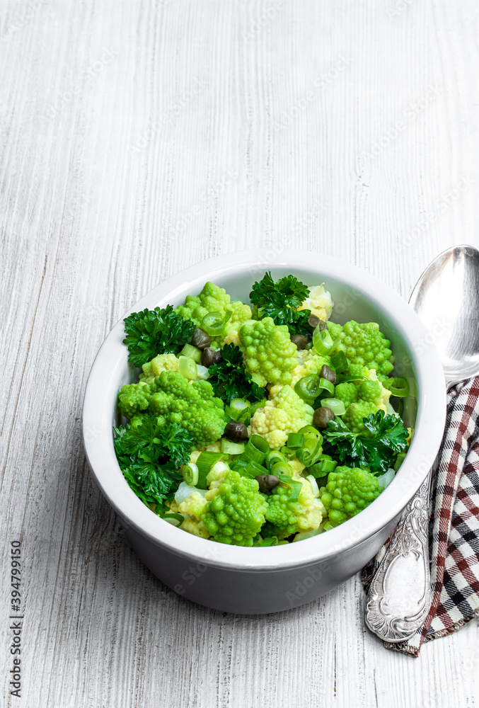 Romanesco cauliflower with capers and onion salad on white wooden table Romanesco cauliflower with capers and onion salad on white wooden table