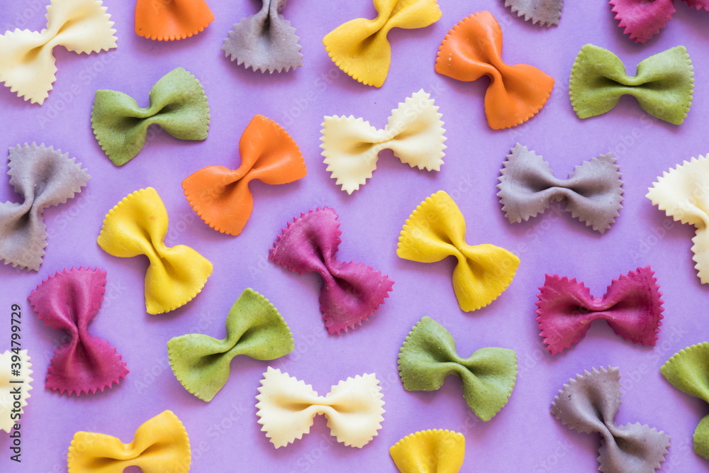 Flat lay and food. Colorful farfalle pasta on a violet flat lay. Food ingredients background. Italian concept. Flat lay and food. Colorful farfalle pasta on a violet flat lay. Food ingredients background. Italian concept.