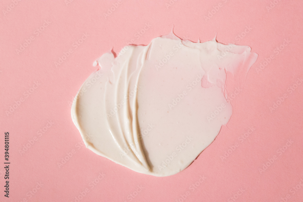 A light cream smear on a flat lay. Smear, mask, cream, light, face, pink background. A light cream smear on a flat lay. Smear, mask, cream, light, face, pink background.
