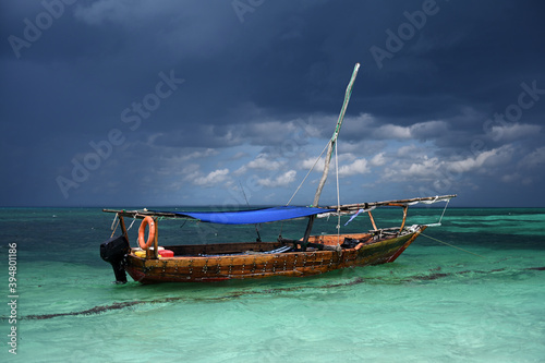 Fototapeta Naklejka Na Ścianę i Meble -  An old wooden fishing boat floats in the ocean. A fishing boat was caught in a storm. The motor boat anchored on the ocean in anticipation of a storm. Beautiful stormy sky. The boat is anchored