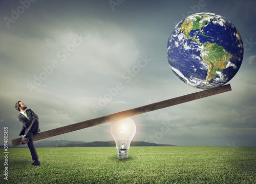 Businessman uses a lightbulb ad lever to lift the World. Earth provided by Nasa. photo
