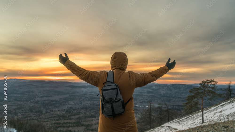 A man raising his hands meets the dawn at the top of the mountain. Tourism, travel, trip. Meditation, energizing outdoors