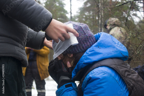 Training in first aid for eye injury. Reportage from a place in the winter forest where the exercises are taking place. Bandaging the victim's head
