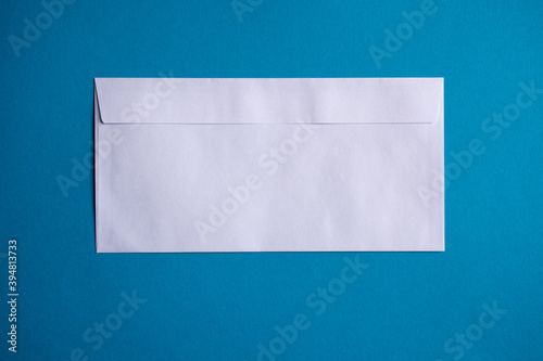 Fotografija Back of a long, white rectangular envelope with a straight flap on a plain blue
