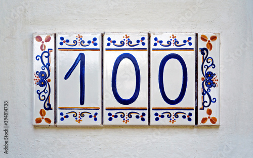 Street sign number 100 on a white wall 
