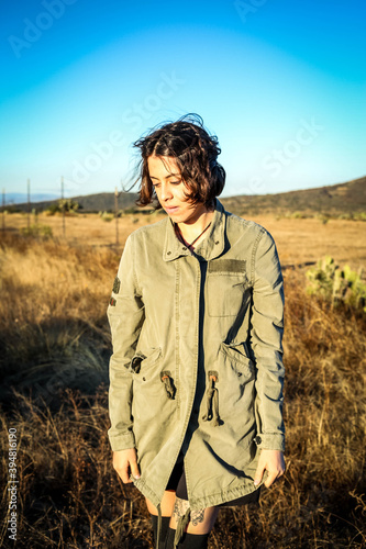 A woman with a glasses and jacke and a road stretching into the distance against the backdrop of mountains