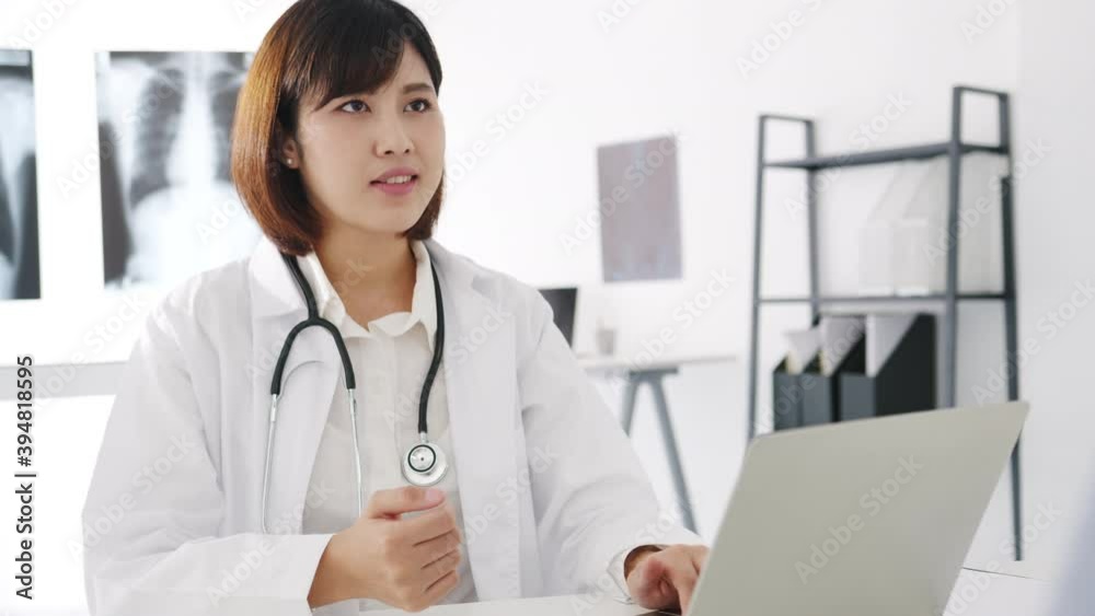 Young Asia female doctor in white medical uniform using computer laptop is delivering great news talk discuss results or symptoms with male patient sit at desk in health clinic or hospital office. Young Asia female doctor in white medical uniform using computer laptop is delivering great news talk discuss results or symptoms with male patient sit at desk in health clinic or hospital office.