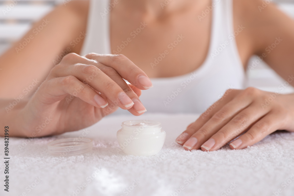Woman taking cream from jar on white towel, closeup Woman taking cream from jar on white towel, closeup