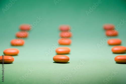 Pile of orange pills on green background.