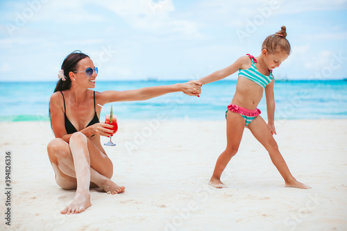 Adorable little girls and young mother on tropical white beach