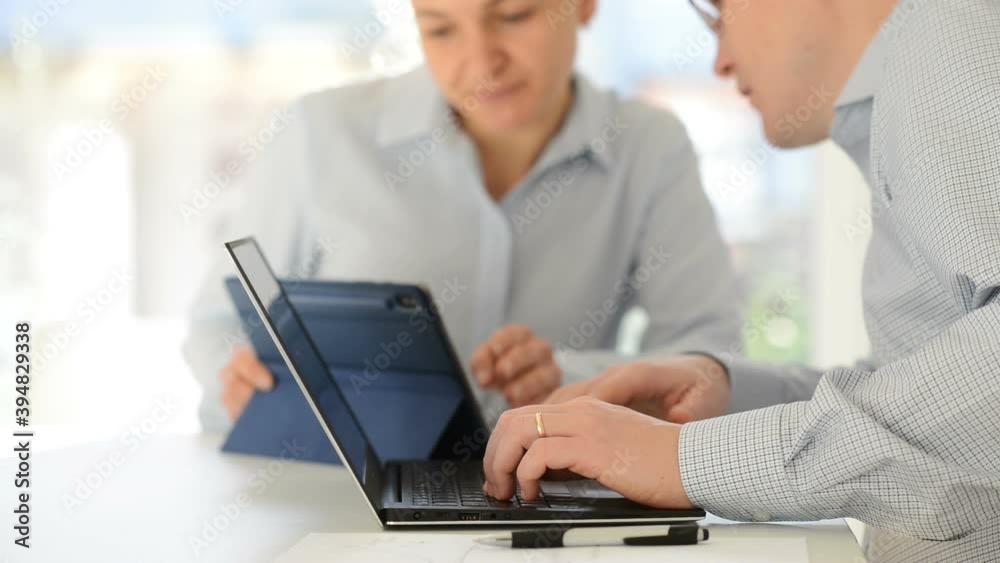 Happy woman and man working and talking together at home office with laptop and tablet Happy woman and man working and talking together at home office with laptop and tablet